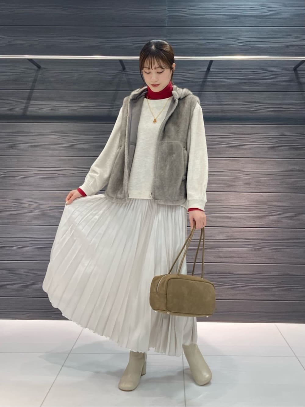 ベージュ系のベスト、ホワイト系のブーツ、ホワイト系のスカートを着用したレディースの秋コーディネートの5枚目の写真