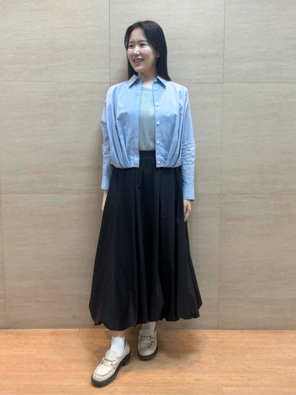 ブラック系のスカート、ブルー系のシャツ/ブラウス、シルバー系のタンクトップを着用したレディースの春コーディネートの2枚目の写真
