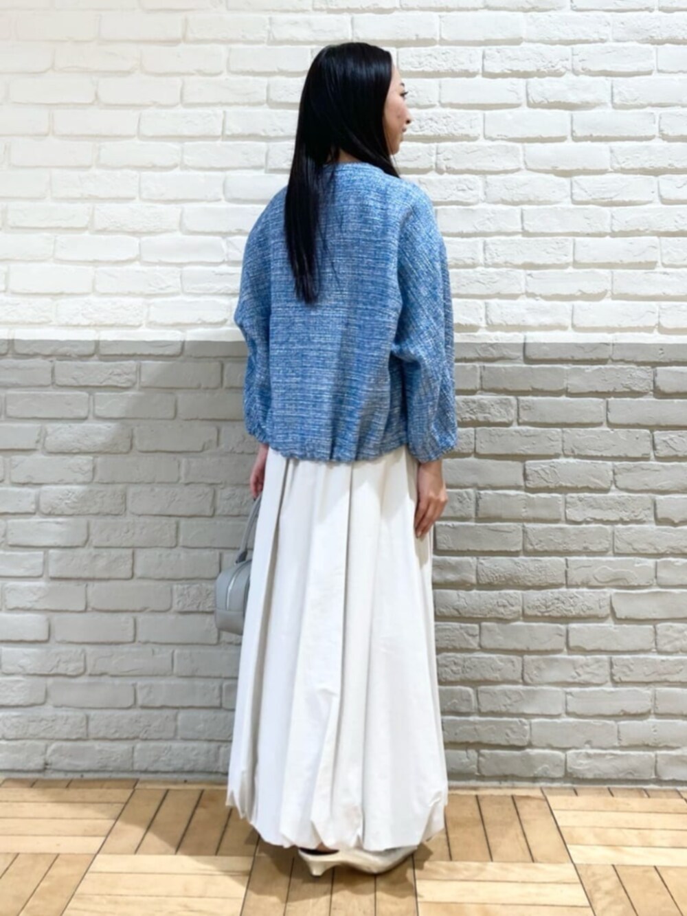 グレー系のスカート、ホワイト系のTシャツ/カットソー、グレー系のボストンバッグを着用したレディースの春コーディネートの3枚目の写真