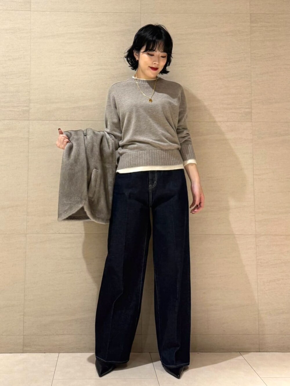 ブルー系のデニムパンツ、ベージュ系のベスト、ブラウン系のニット/セーターを着用したレディースの秋コーディネートの8枚目の写真