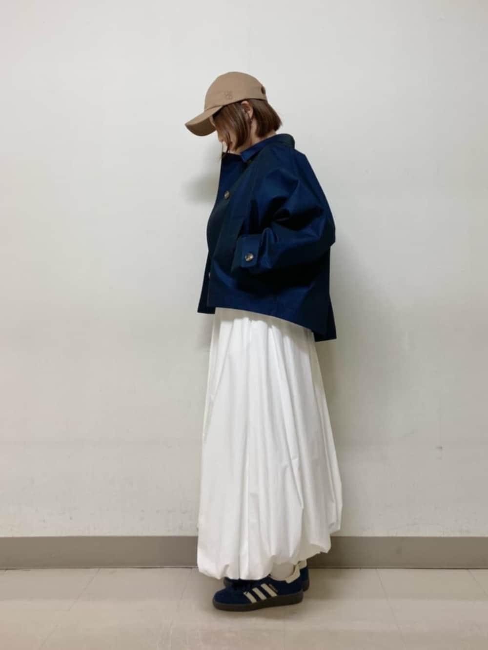 ホワイト系のスカート、ブルー系のブルゾン、イエロー系のキャップを着用したレディースの春コーディネートの3枚目の写真