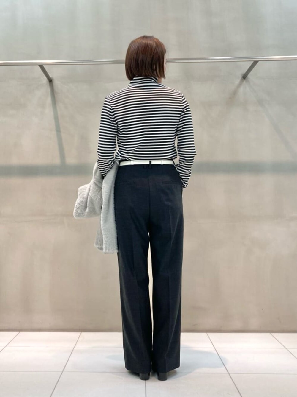 グレー系のスーツパンツ、ブラック系のブーツ、ベージュ系のパーカーを着用したレディースの秋コーディネートの10枚目の写真