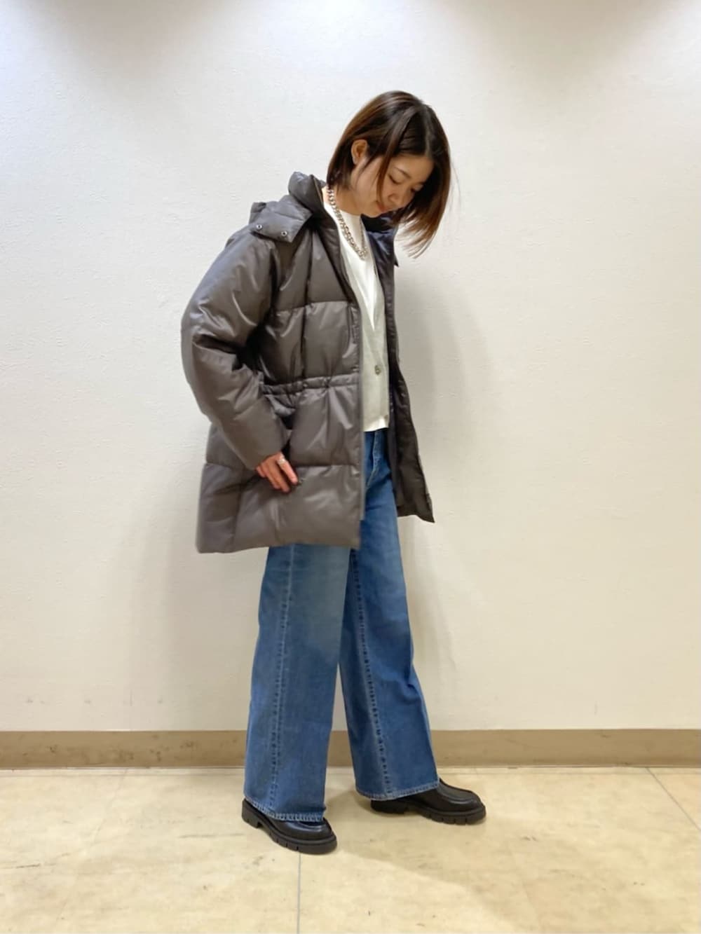 ブルー系のデニムパンツ、グレー系のダウンジャケット/コート、ベージュ系のカーディガン/ボレロを着用したレディースの冬コーディネートの3枚目の写真