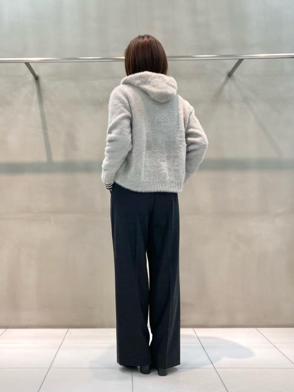 グレー系のスーツパンツ、ブラック系のブーツ、ベージュ系のパーカーを着用したレディースの秋コーディネートの6枚目の写真