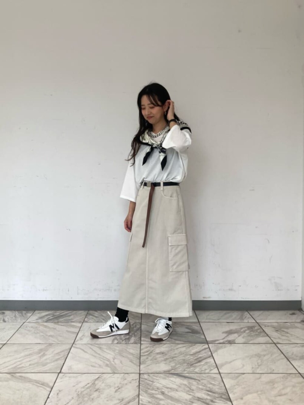 ホワイト系のTシャツ/カットソー、ベージュ系のスカート、ブラック系のストール/ショールを着用したレディースの春コーディネートの3枚目の写真