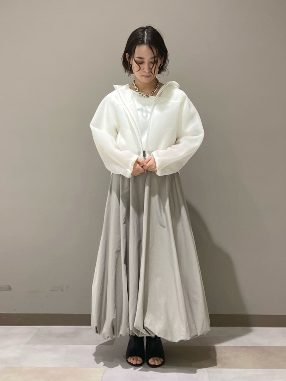 ベージュ系のスカート、ホワイト系のTシャツ/カットソー、ブラック系のサンダルを着用したレディースの春コーディネートの5枚目の写真