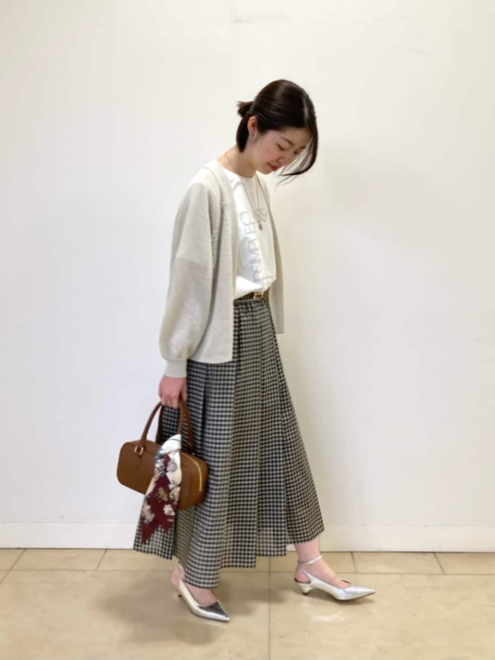 ベージュ系のカーディガン/ボレロ、ホワイト系のTシャツ/カットソー、ブラック系のスカートを着用したレディースの春コーディネートの2枚目の写真