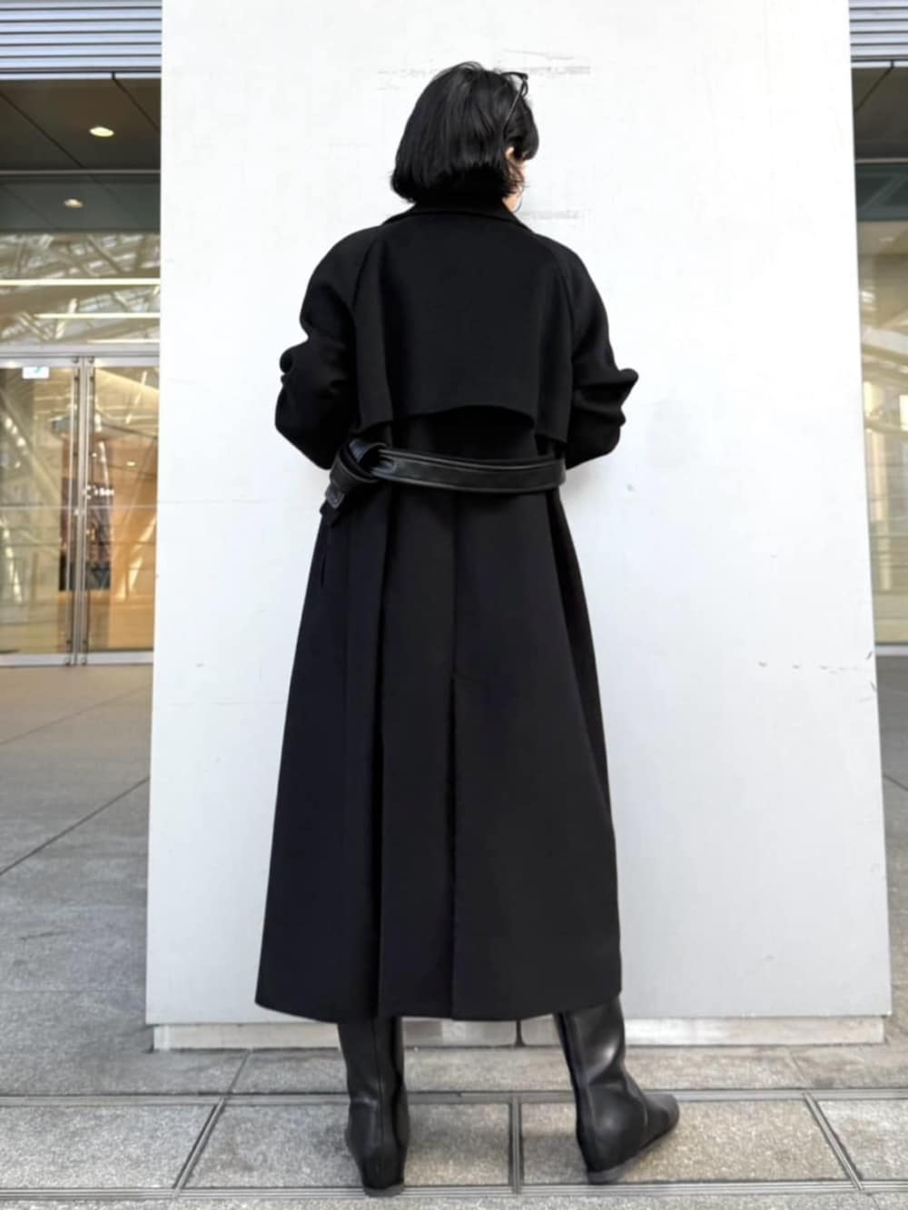 ブラック系のトレンチコート、グレー系のニット/セーターを着用したレディースの冬コーディネートの2枚目の写真