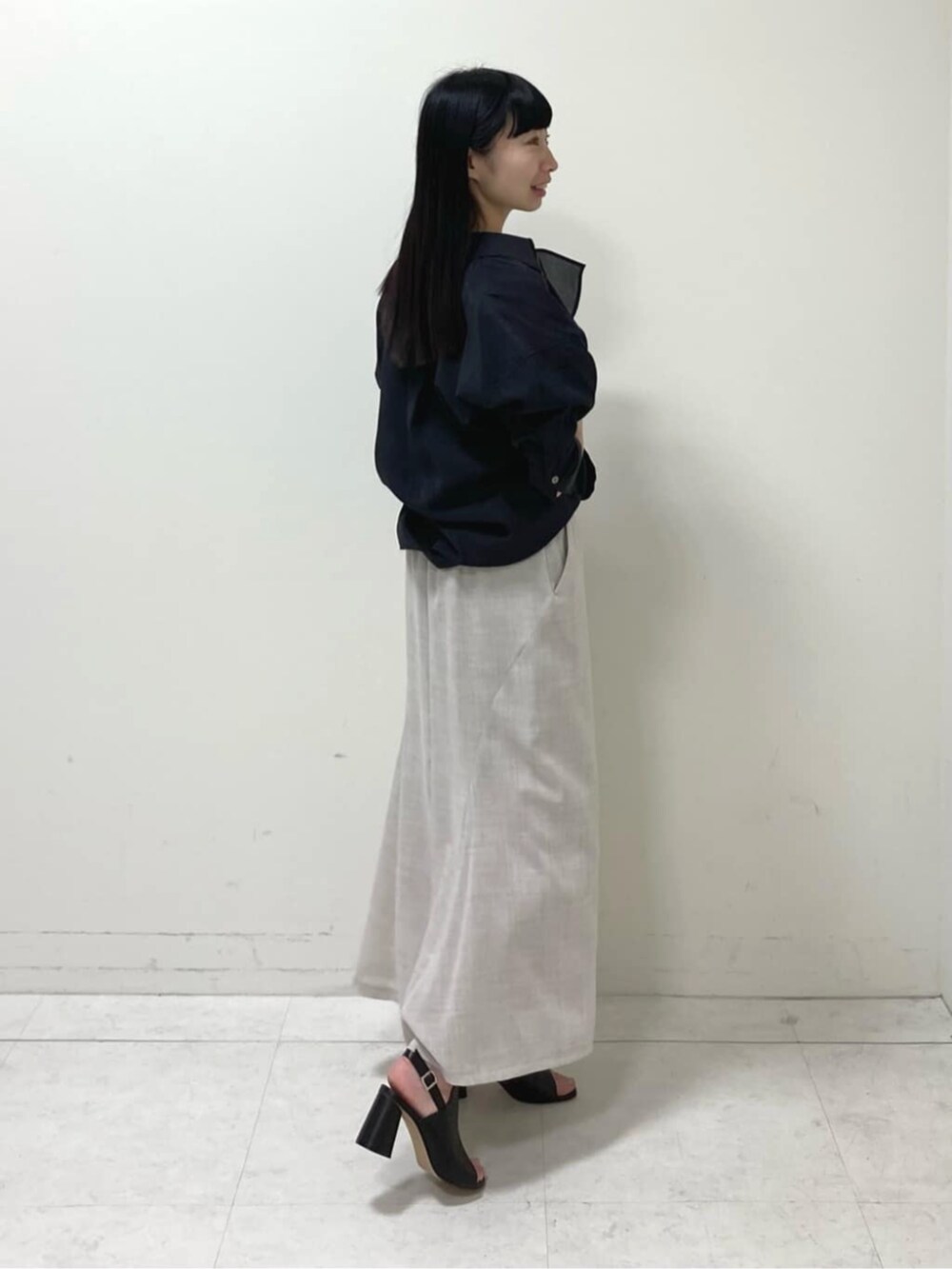 ブラック系のシャツ/ブラウス、ホワイト系のスカート、ブラック系のサンダルを着用したレディースの春コーディネートの3枚目の写真