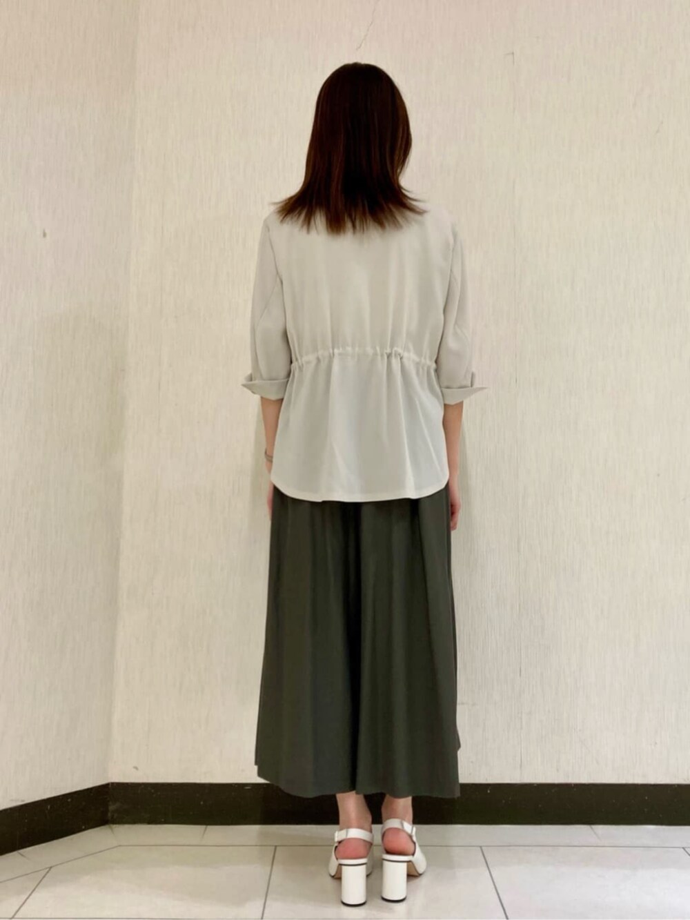 ベージュ系のテーラードジャケット、ホワイト系のTシャツ/カットソー、グリーン系のパンツを着用したレディースの夏コーディネートの5枚目の写真