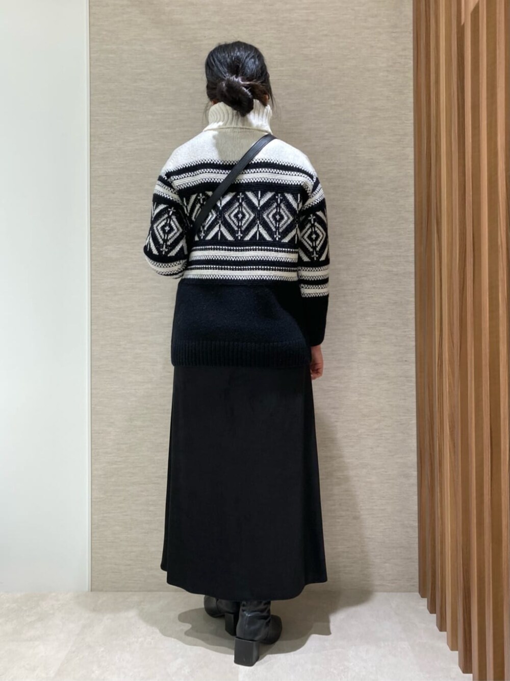 ブラック系のスカート、ブラック系のショルダーバッグ、ブラック系のニット/セーターを着用したレディースの冬コーディネートの3枚目の写真