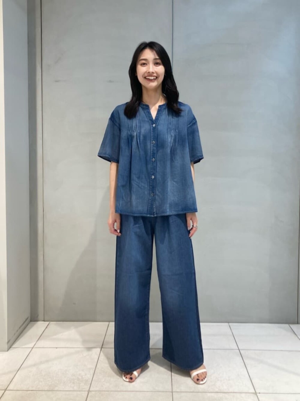 ブラウン系のクラッチバッグ、ブルー系のシャツ/ブラウス、ブルー系のデニムパンツを着用したレディースの夏コーディネートの4枚目の写真