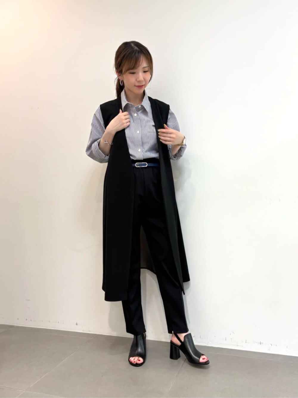 ブルー系のシャツ/ブラウス、ブラック系のサンダル、ブラック系のベストを着用したレディースの春コーディネートの3枚目の写真