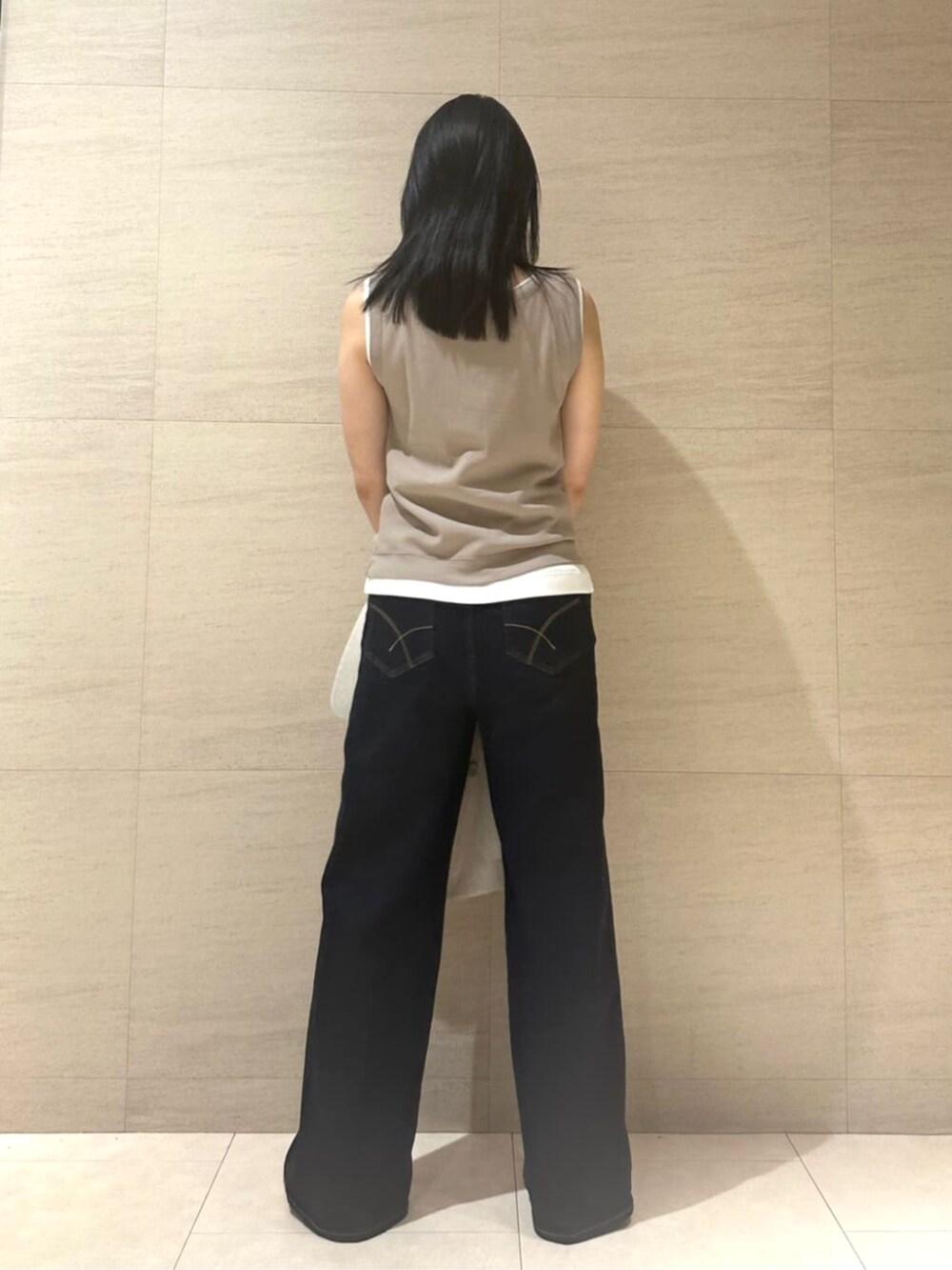 ブルー系のデニムパンツ、ベージュ系のテーラードジャケット、ベージュ系のタンクトップを着用したレディースの夏コーディネートの6枚目の写真