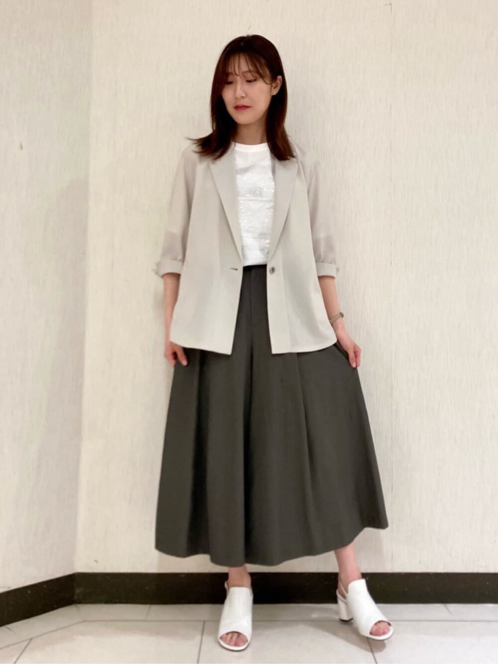ベージュ系のテーラードジャケット、ホワイト系のTシャツ/カットソー、グリーン系のパンツを着用したレディースの夏コーディネートの3枚目の写真