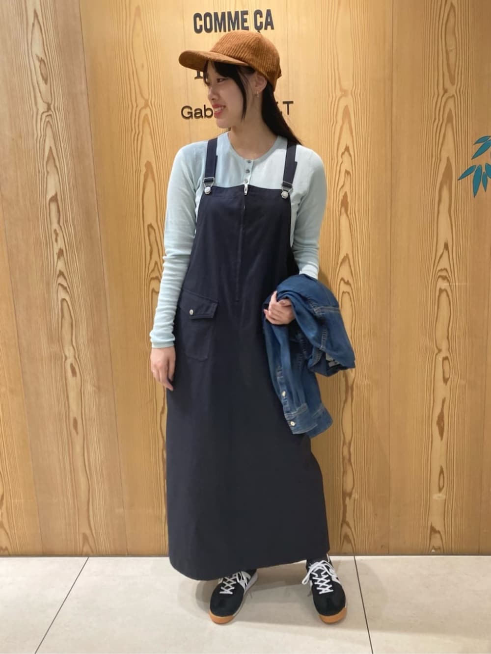 ブルー系のシャツ/ブラウス、ブルー系のジャンパースカート、イエロー系のキャップを着用したレディースの秋コーディネートの3枚目の写真