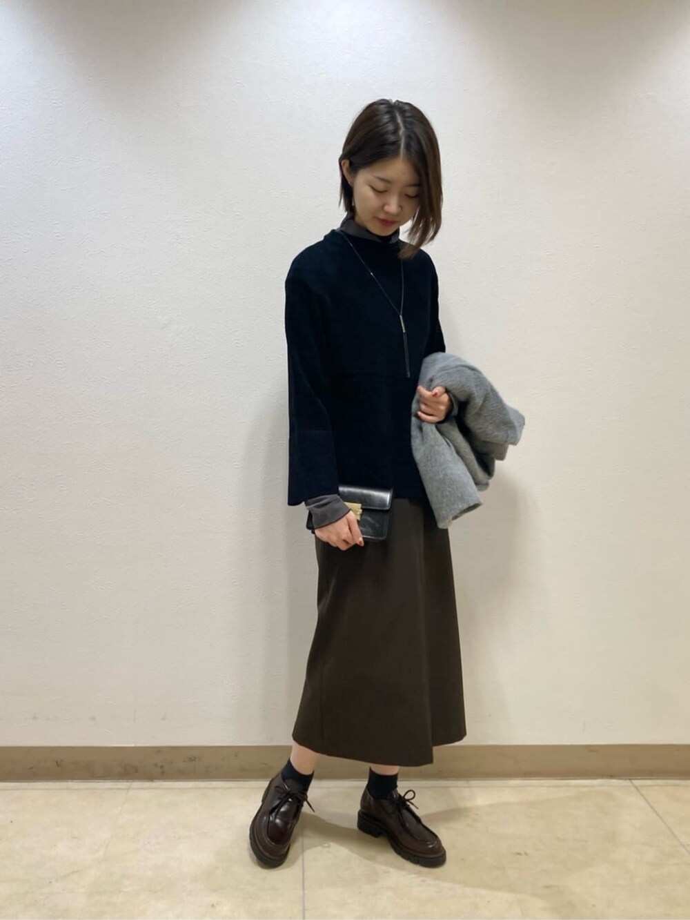 グレー系のその他アウター、ブラック系のスカートを着用したレディースの冬コーディネートの5枚目の写真