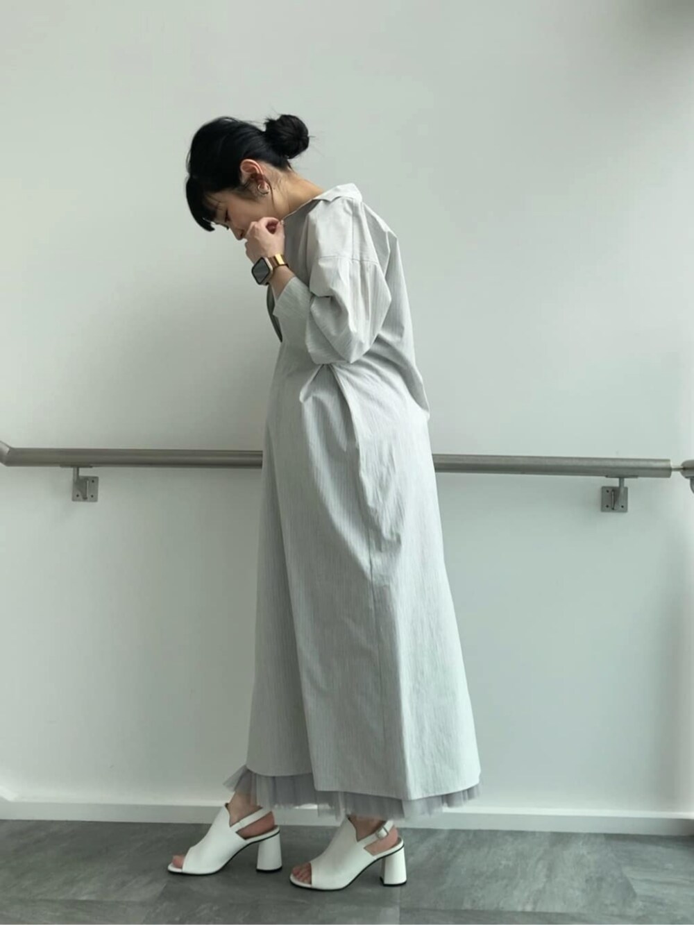 グレー系のスカート、ホワイト系のサンダル、グレー系のシャツワンピースを着用したレディースの春コーディネートの3枚目の写真