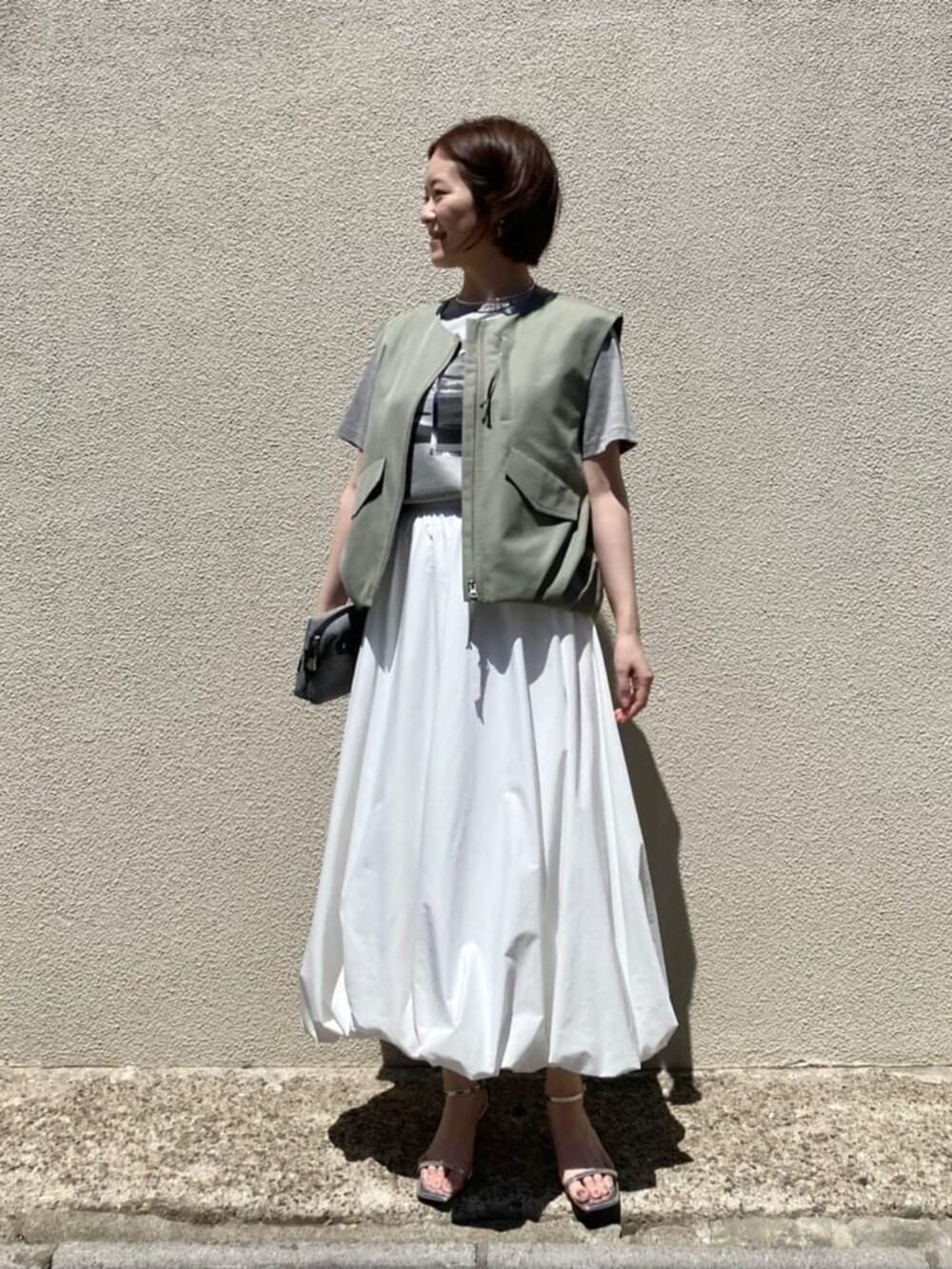 ホワイト系のスカート、ベージュ系のTシャツ/カットソーを着用したレディースの夏コーディネートの4枚目の写真