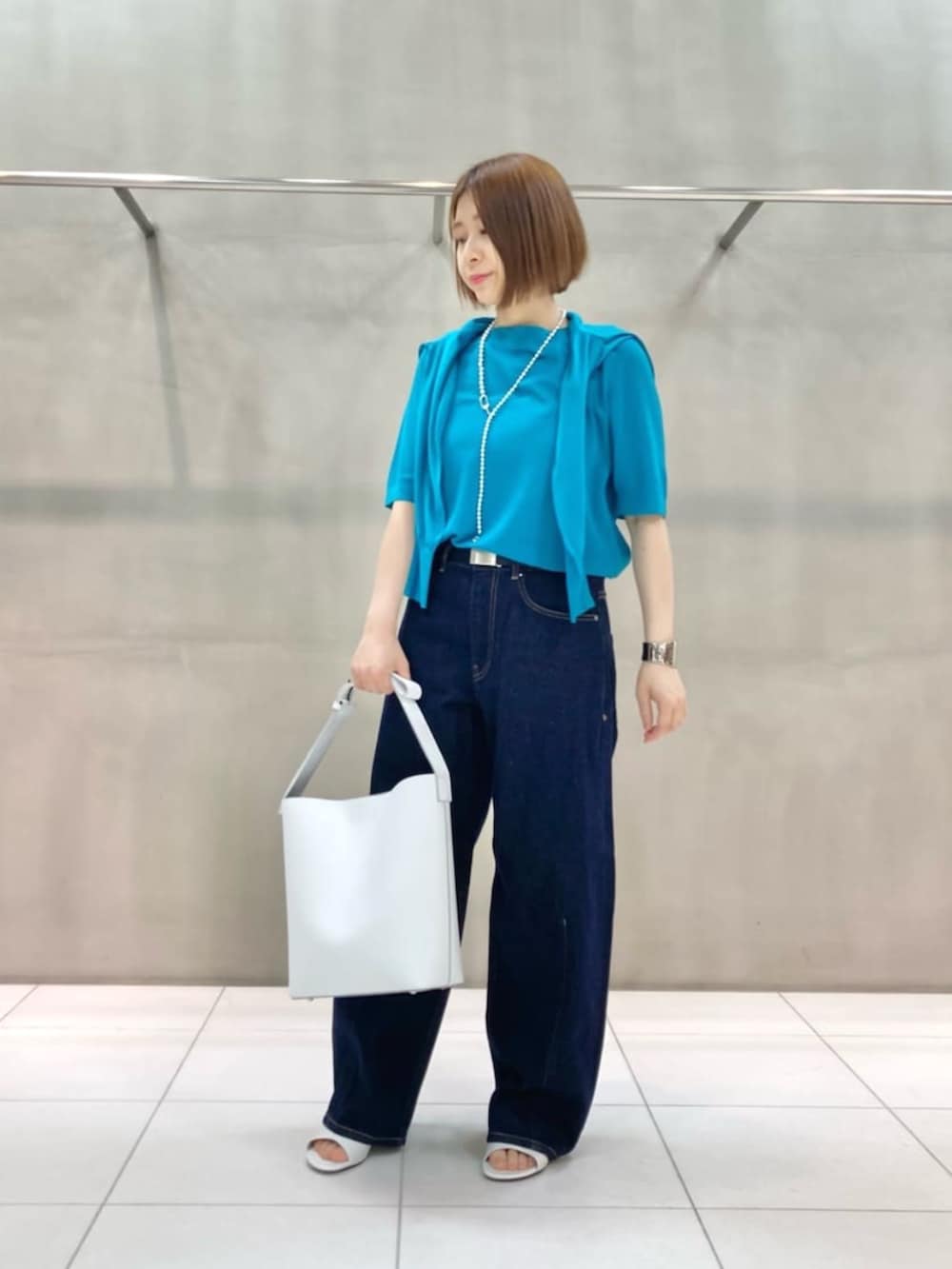 ホワイト系のショルダーバッグ、ブルー系のデニムパンツ、グリーン系のカーディガン/ボレロを着用したレディースの春コーディネートの2枚目の写真