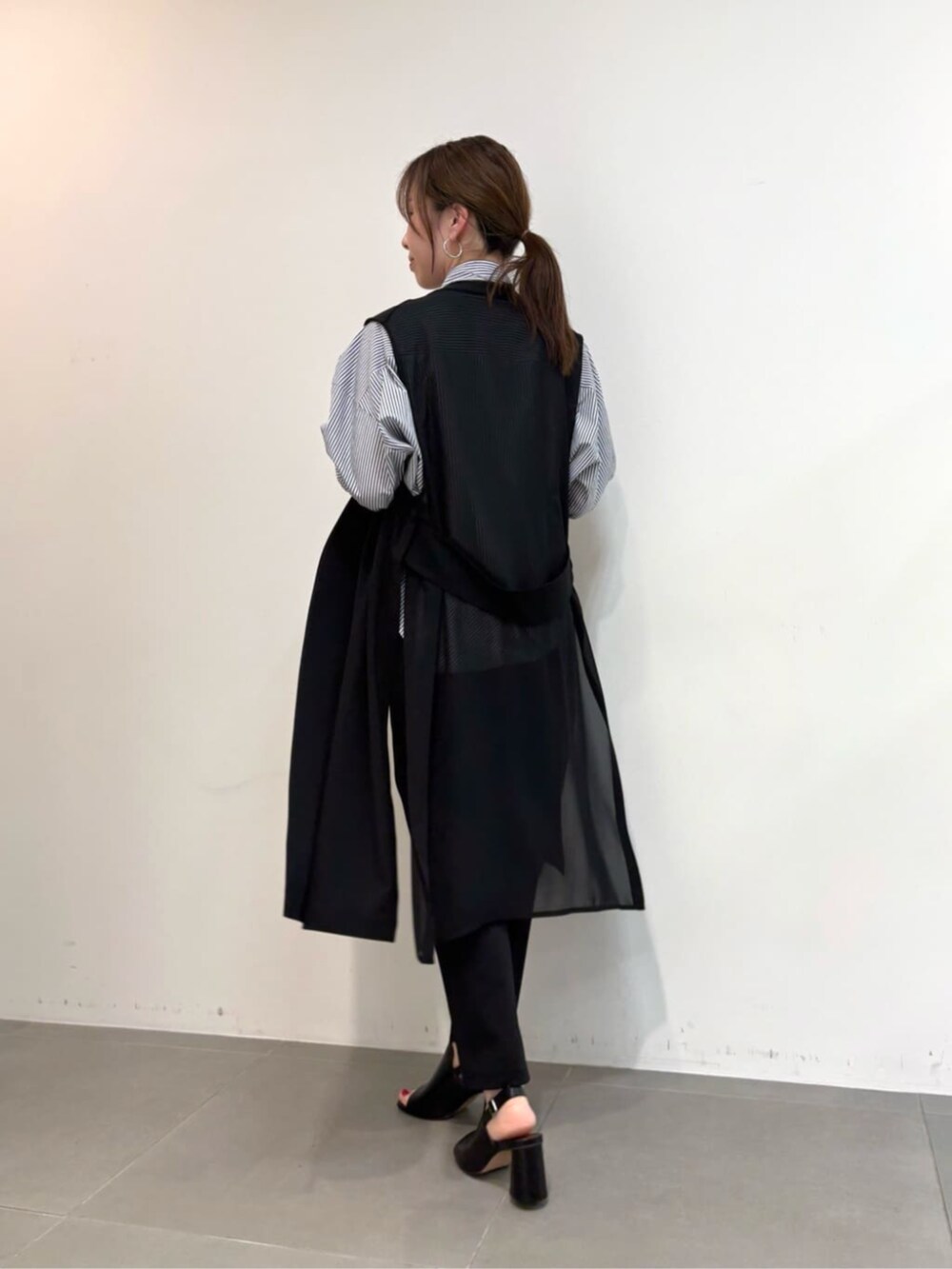 ブルー系のシャツ/ブラウス、ブラック系のサンダル、ブラック系のベストを着用したレディースの春コーディネートの7枚目の写真