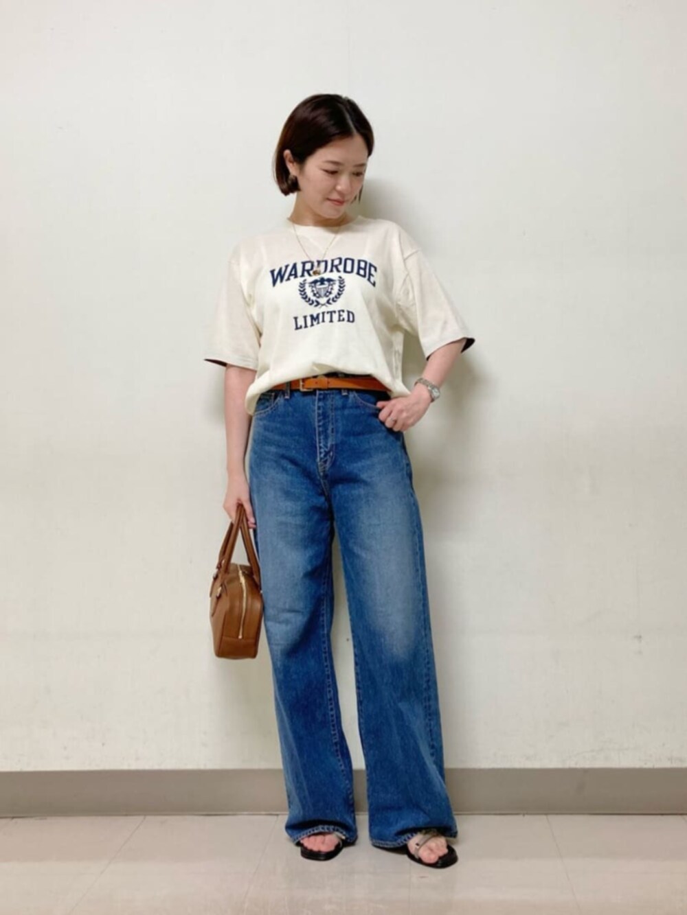 ブラウン系のボストンバッグ、ブルー系のデニムパンツ、ホワイト系のニット/セーターを着用したレディースの春コーディネートの5枚目の写真