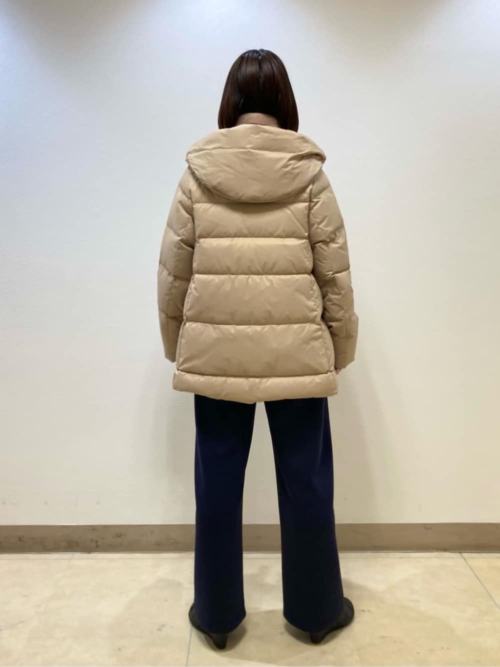 ベージュ系のダウンジャケット/コート、ブルー系のスラックスを着用したレディースの冬コーディネートの5枚目の写真