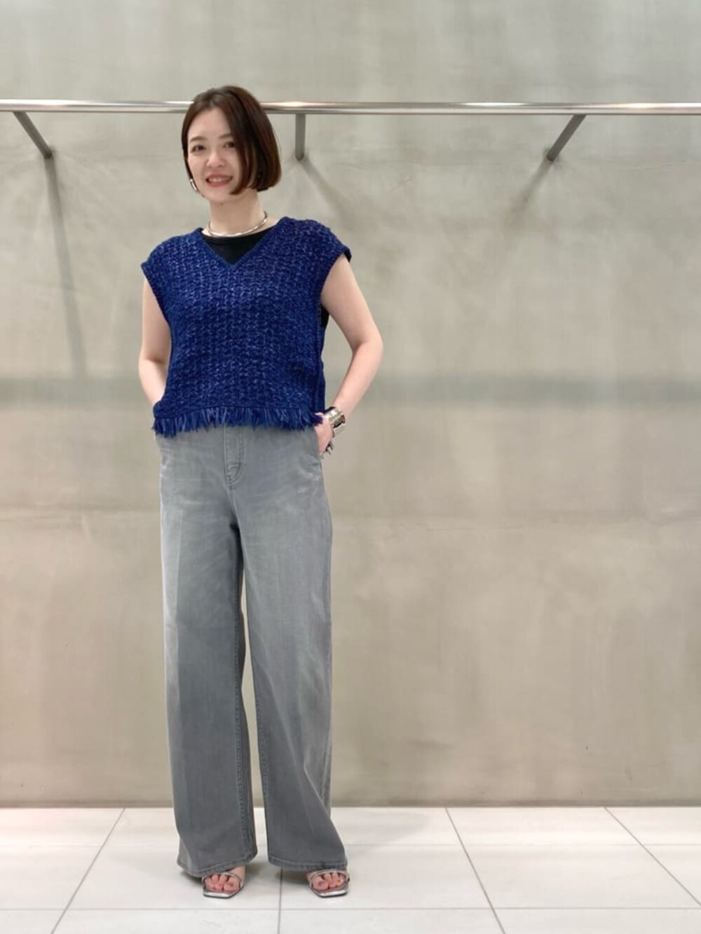 グレー系のデニムパンツ、ブルー系のニット/セーター、シルバー系のブレスレットを着用したレディースの春コーディネートの4枚目の写真