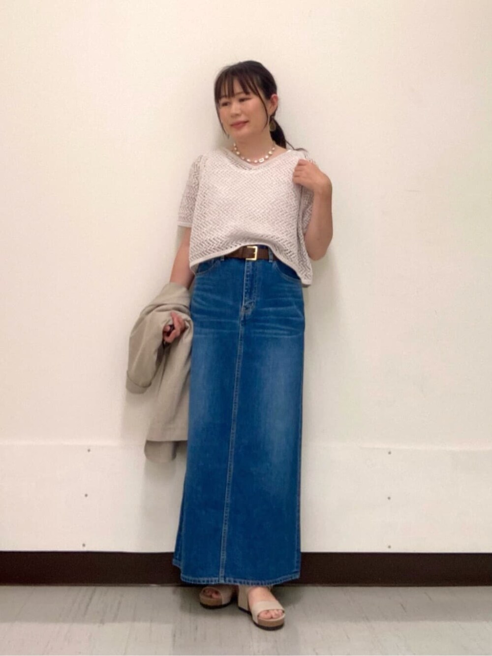 グレー系のスカート、ベージュ系のテーラードジャケット、グレー系のアンサンブルを着用したレディースの夏コーディネートの2枚目の写真