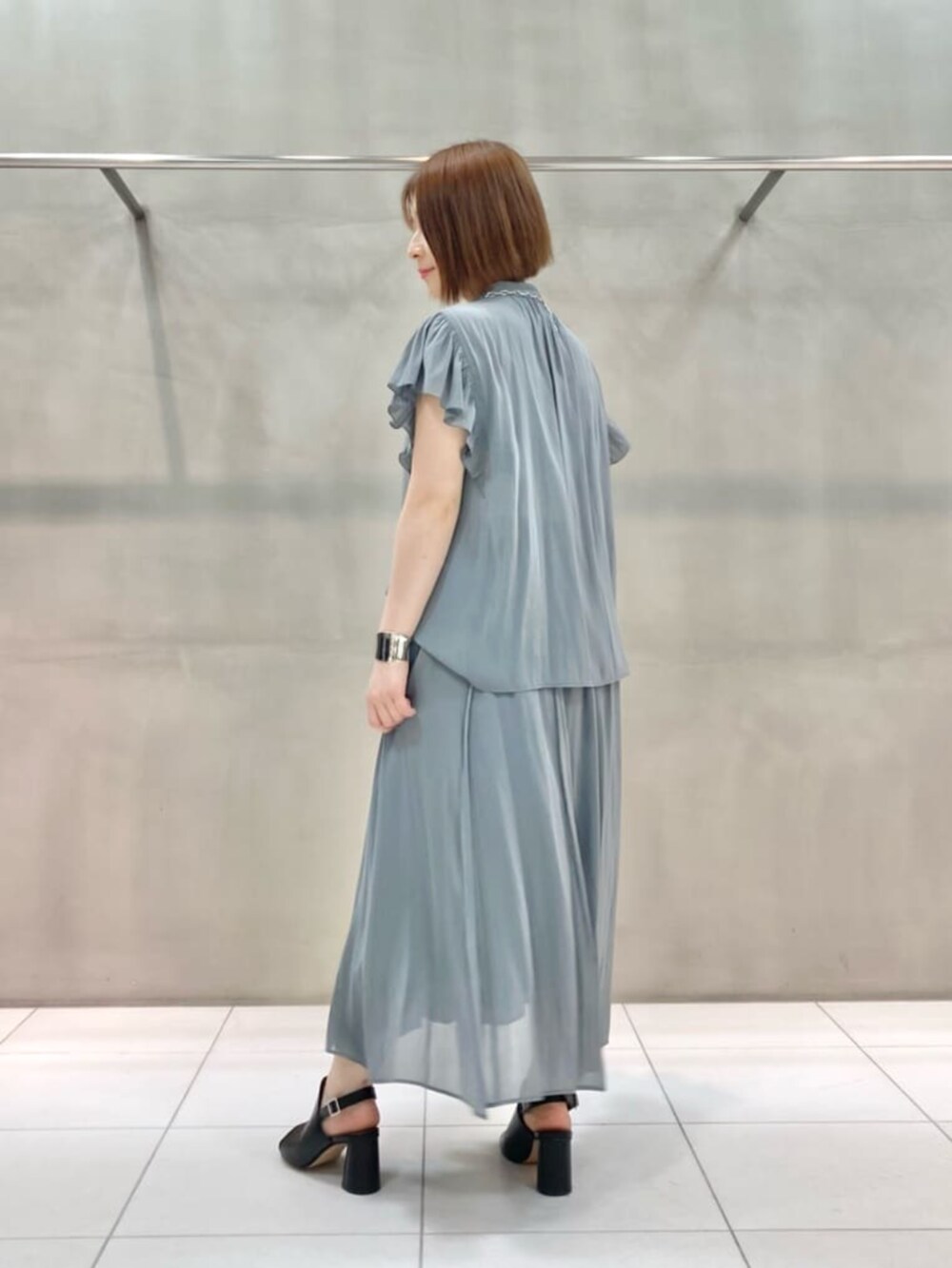 ブラック系のサンダル、グレー系のカーディガン/ボレロ、グリーン系のスカートを着用したレディースの春コーディネートの5枚目の写真