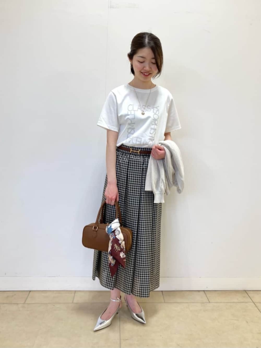 ベージュ系のカーディガン/ボレロ、ホワイト系のTシャツ/カットソー、ブラック系のスカートを着用したレディースの春コーディネートの4枚目の写真