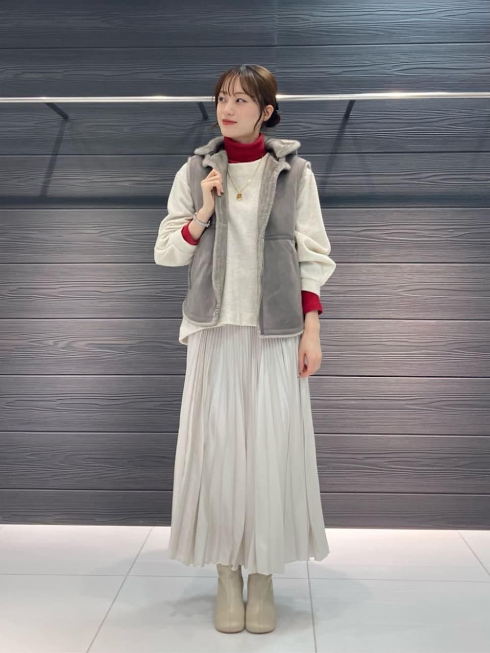 ベージュ系のベスト、ホワイト系のブーツ、ホワイト系のスカートを着用したレディースの秋コーディネートの3枚目の写真