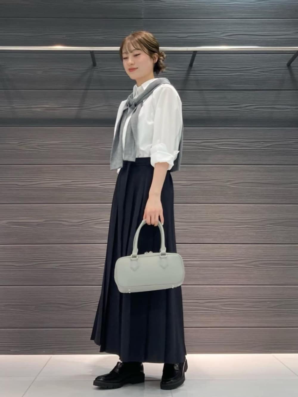 ブラック系のその他シューズ、ホワイト系のシャツ/ブラウス、ブルー系のスカートを着用したレディースの春コーディネートの2枚目の写真