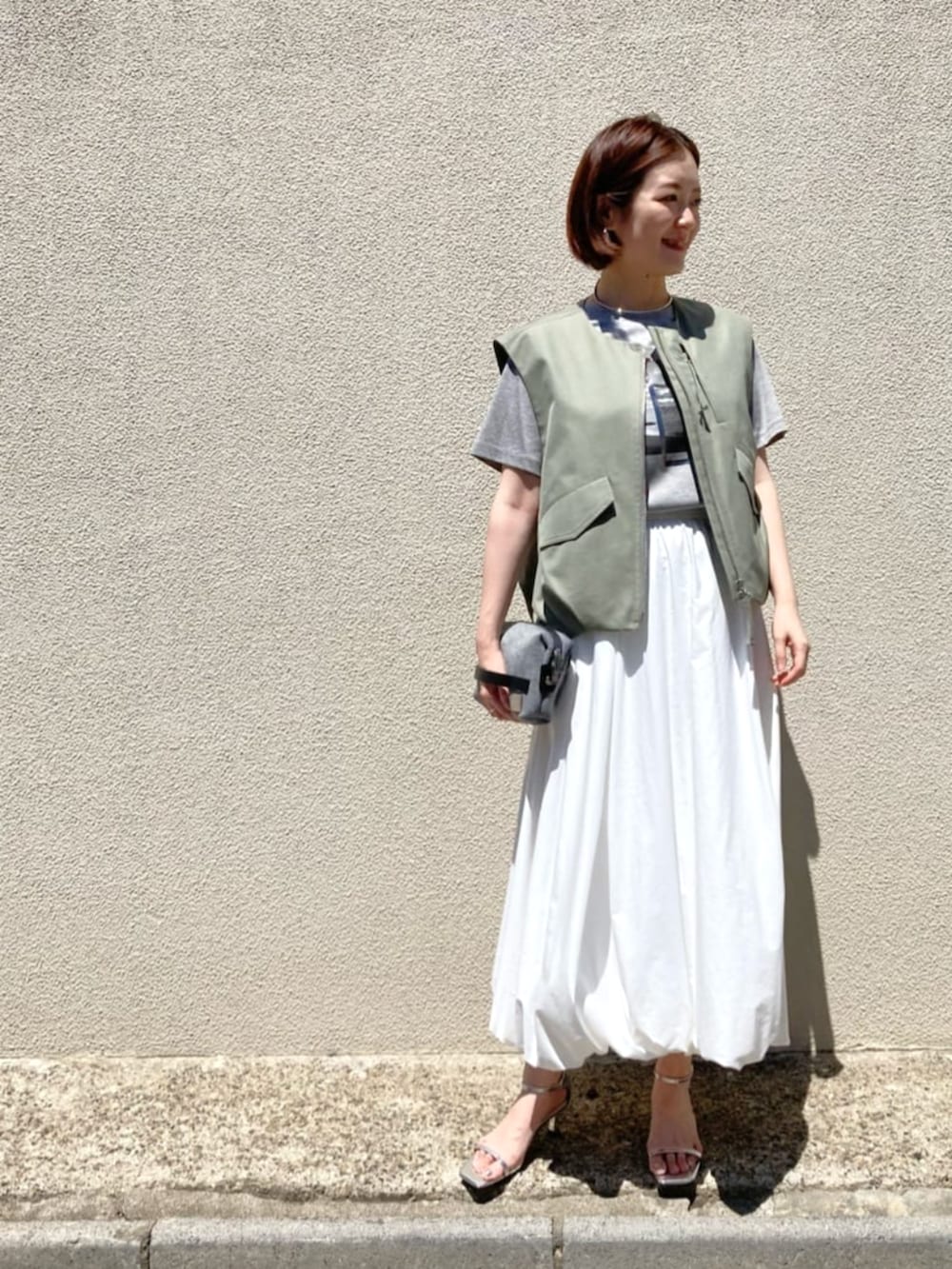 ホワイト系のスカート、ベージュ系のTシャツ/カットソーを着用したレディースの夏コーディネートの5枚目の写真