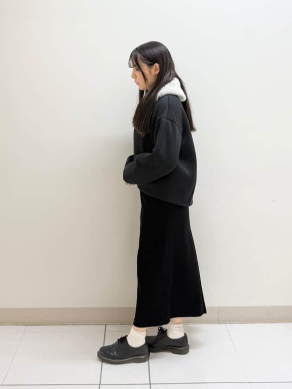 ベージュ系のパーカー、ブラック系のスカート、ブラック系のブルゾンを着用したレディースの冬コーディネートの2枚目の写真
