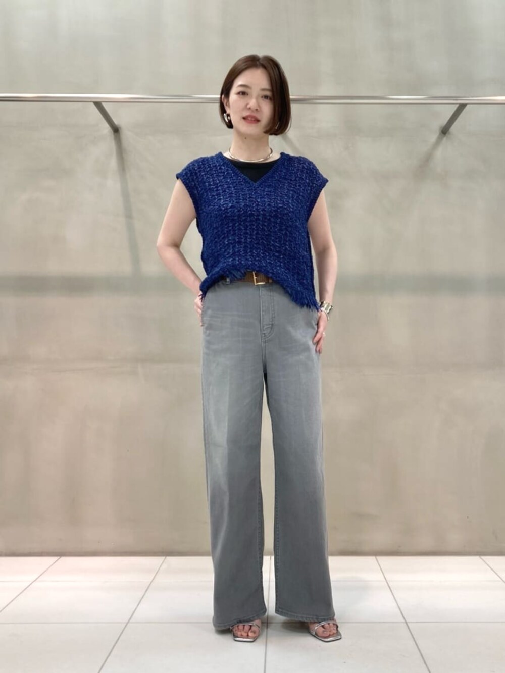 グレー系のデニムパンツ、ブルー系のニット/セーター、シルバー系のブレスレットを着用したレディースの春コーディネートの5枚目の写真