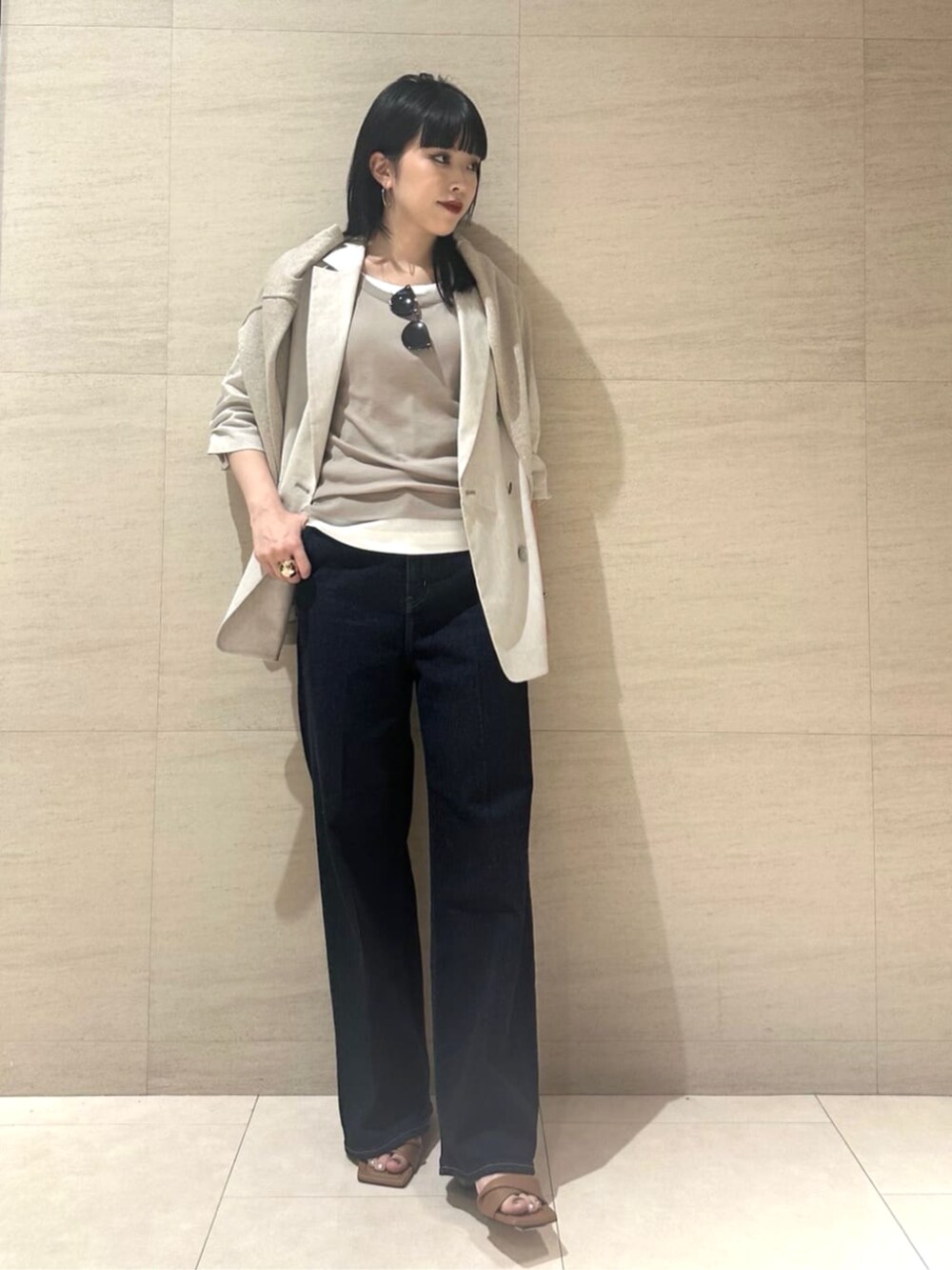 ブルー系のデニムパンツ、ベージュ系のテーラードジャケット、ベージュ系のタンクトップを着用したレディースの夏コーディネートの2枚目の写真