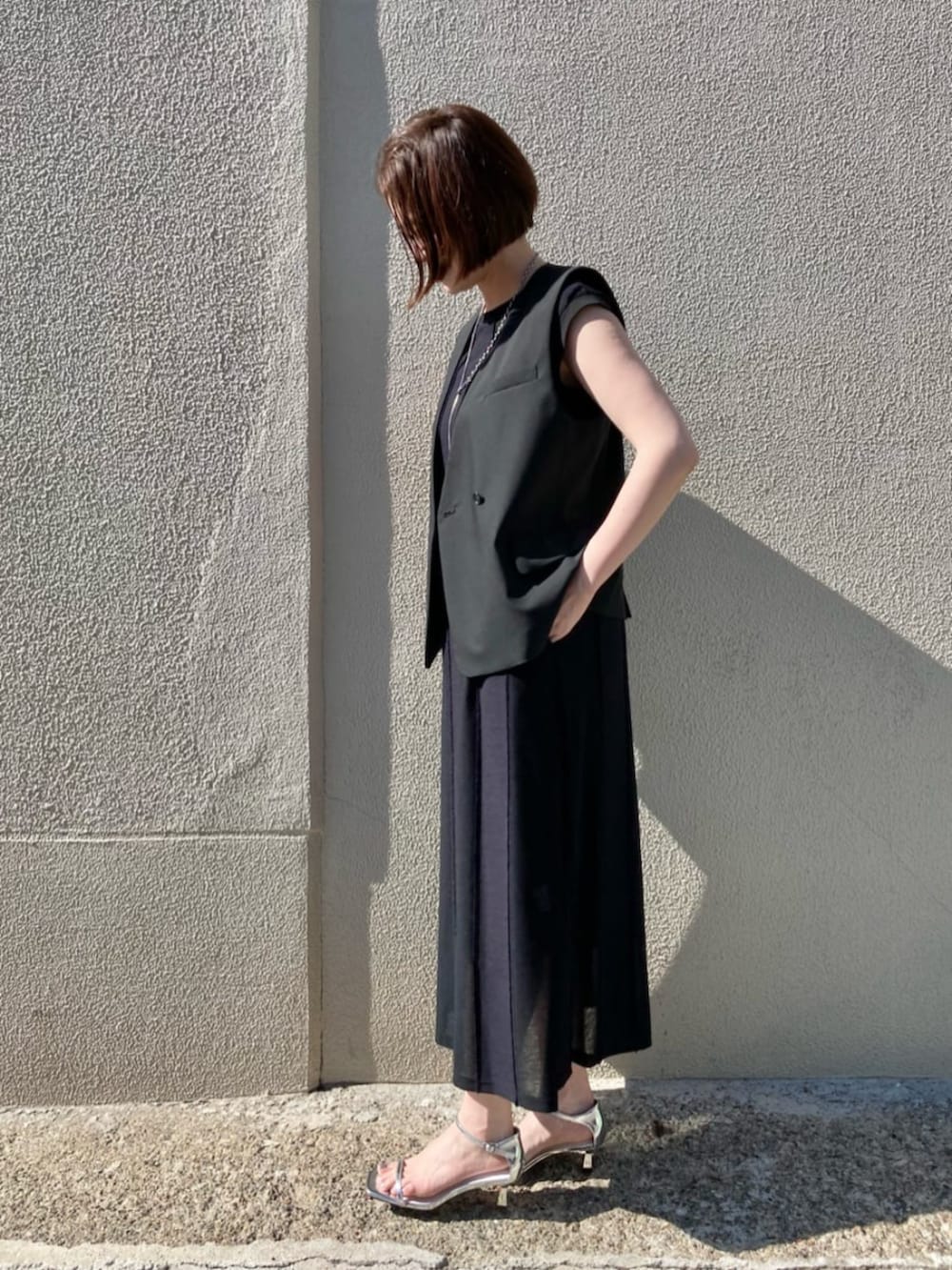 ブラック系のベストを着用したレディースの夏コーディネートの3枚目の写真