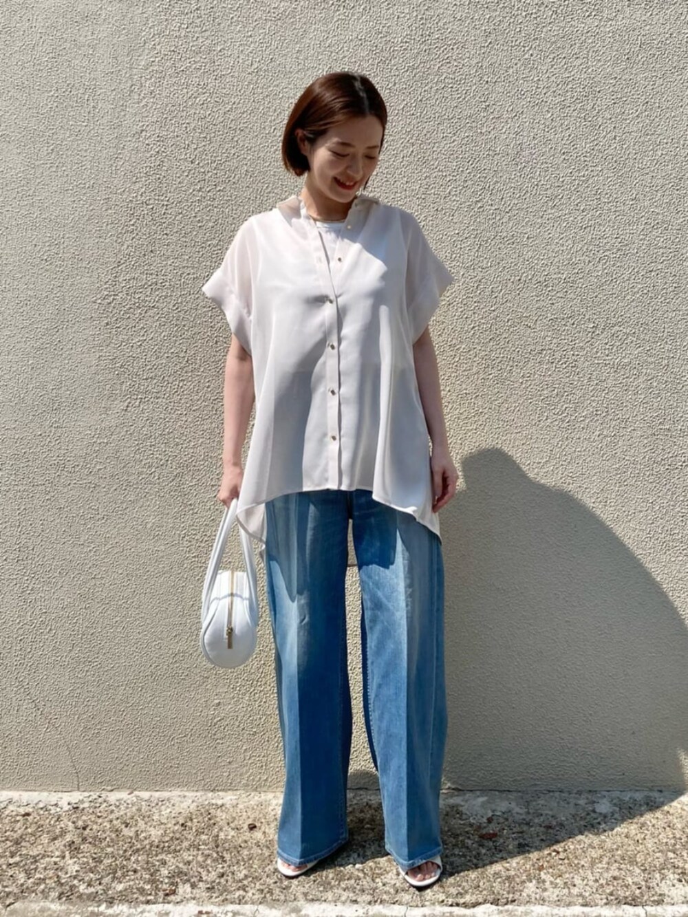 ブルー系のデニムパンツ、ホワイト系のサンダル、ホワイト系のシャツ/ブラウスを着用したレディースの夏コーディネートの3枚目の写真