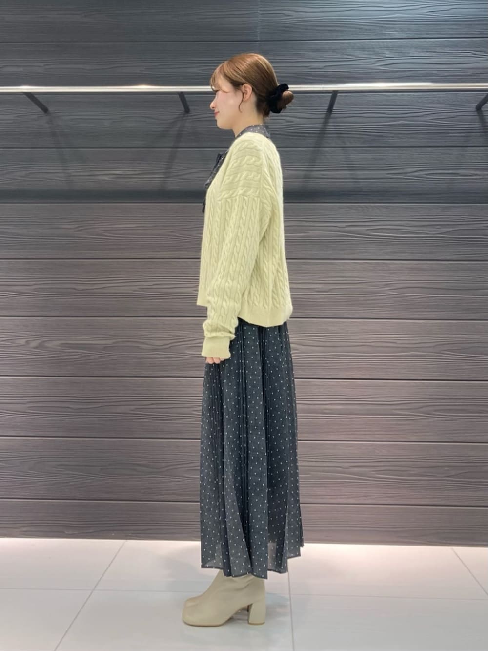 ホワイト系のブーツ、イエロー系のニット/セーター、グレー系のスカートを着用したレディースの冬コーディネートの3枚目の写真