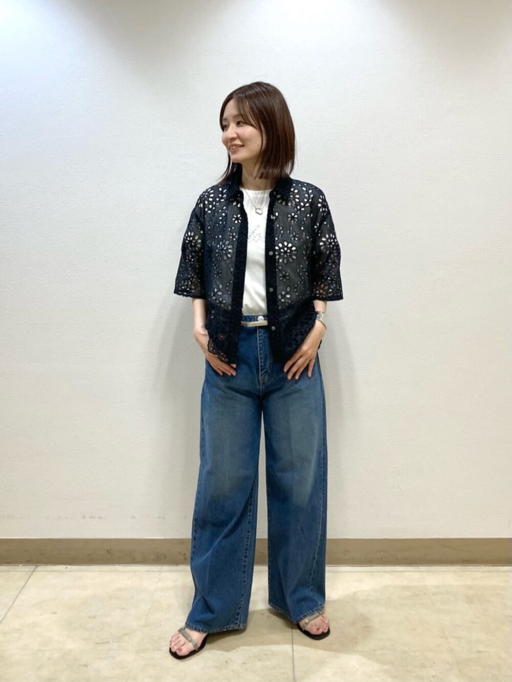 ブルー系のデニムパンツ、ブラック系のシャツ/ブラウス、グレー系のサンダルを着用したレディースの春コーディネートの2枚目の写真