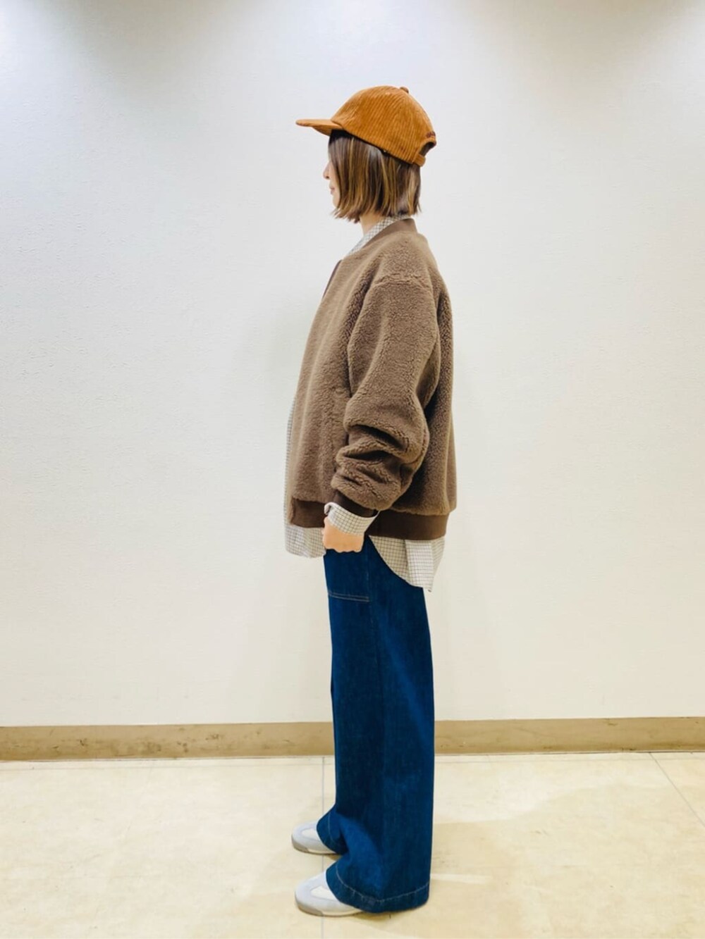 ブラウン系のブルゾン、ブルー系のデニムパンツ、イエロー系のキャップを着用したレディースの秋コーディネートの5枚目の写真