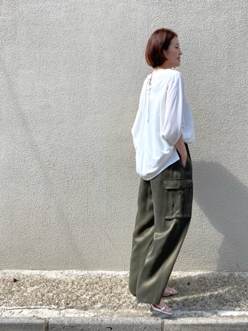 グリーン系のパンツ、ホワイト系のトップスを着用したレディースの夏コーディネートの3枚目の写真