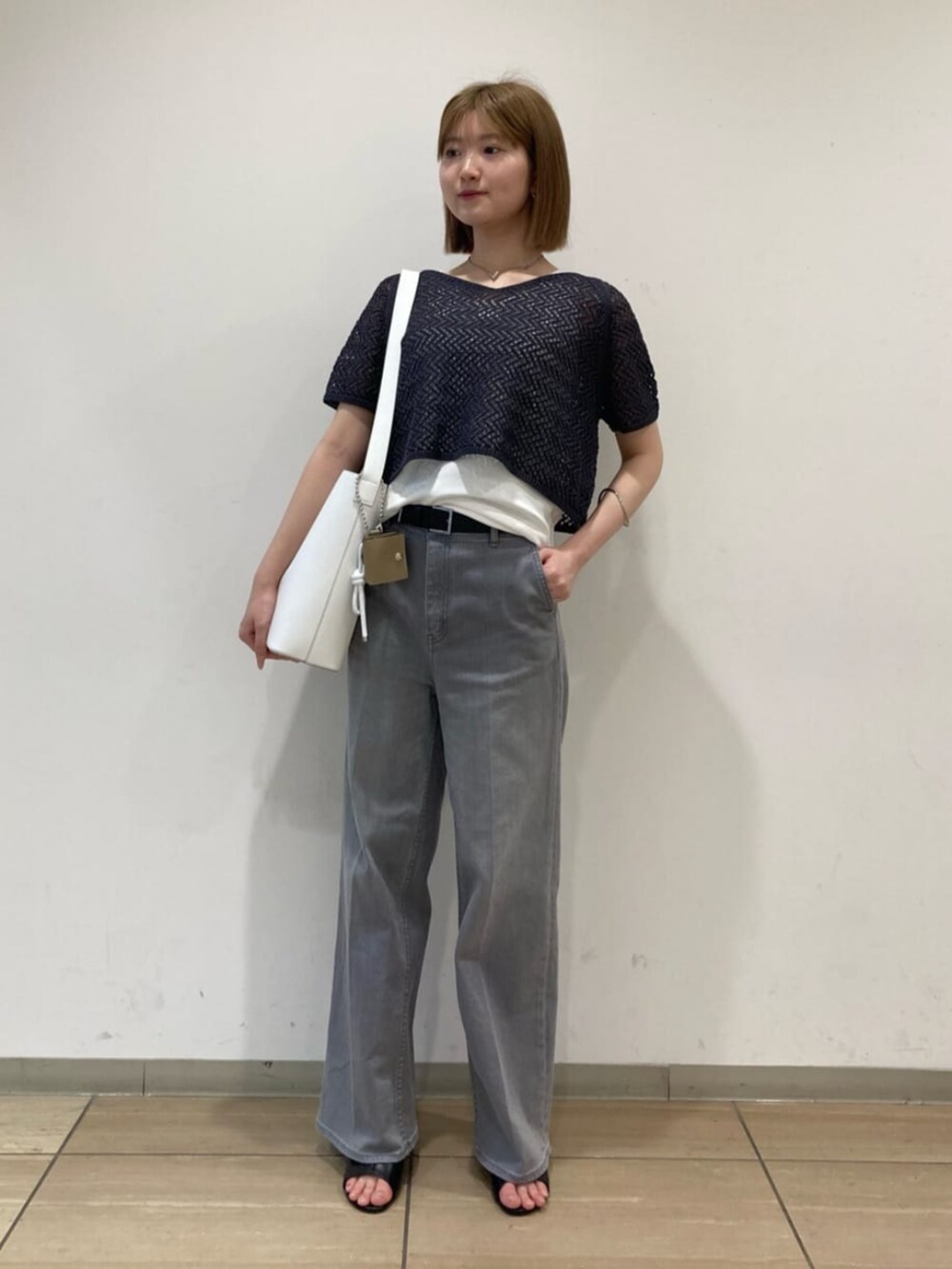 ホワイト系のショルダーバッグ、グレー系のデニムパンツ、グレー系のアンサンブルを着用したレディースの秋コーディネートの3枚目の写真