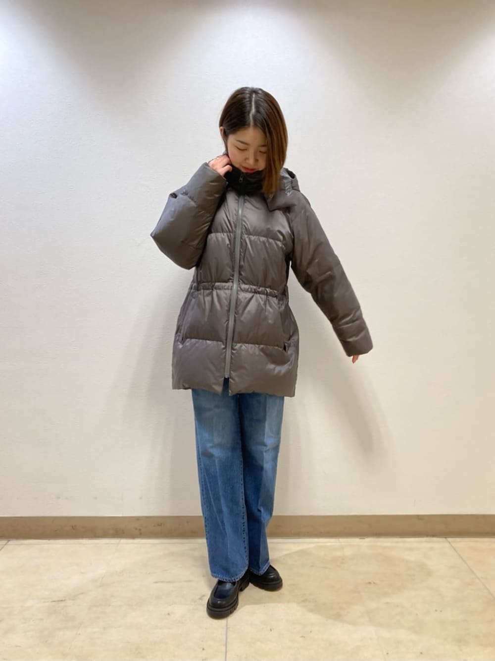 ブルー系のデニムパンツ、グレー系のダウンジャケット/コート、ベージュ系のカーディガン/ボレロを着用したレディースの冬コーディネートの5枚目の写真