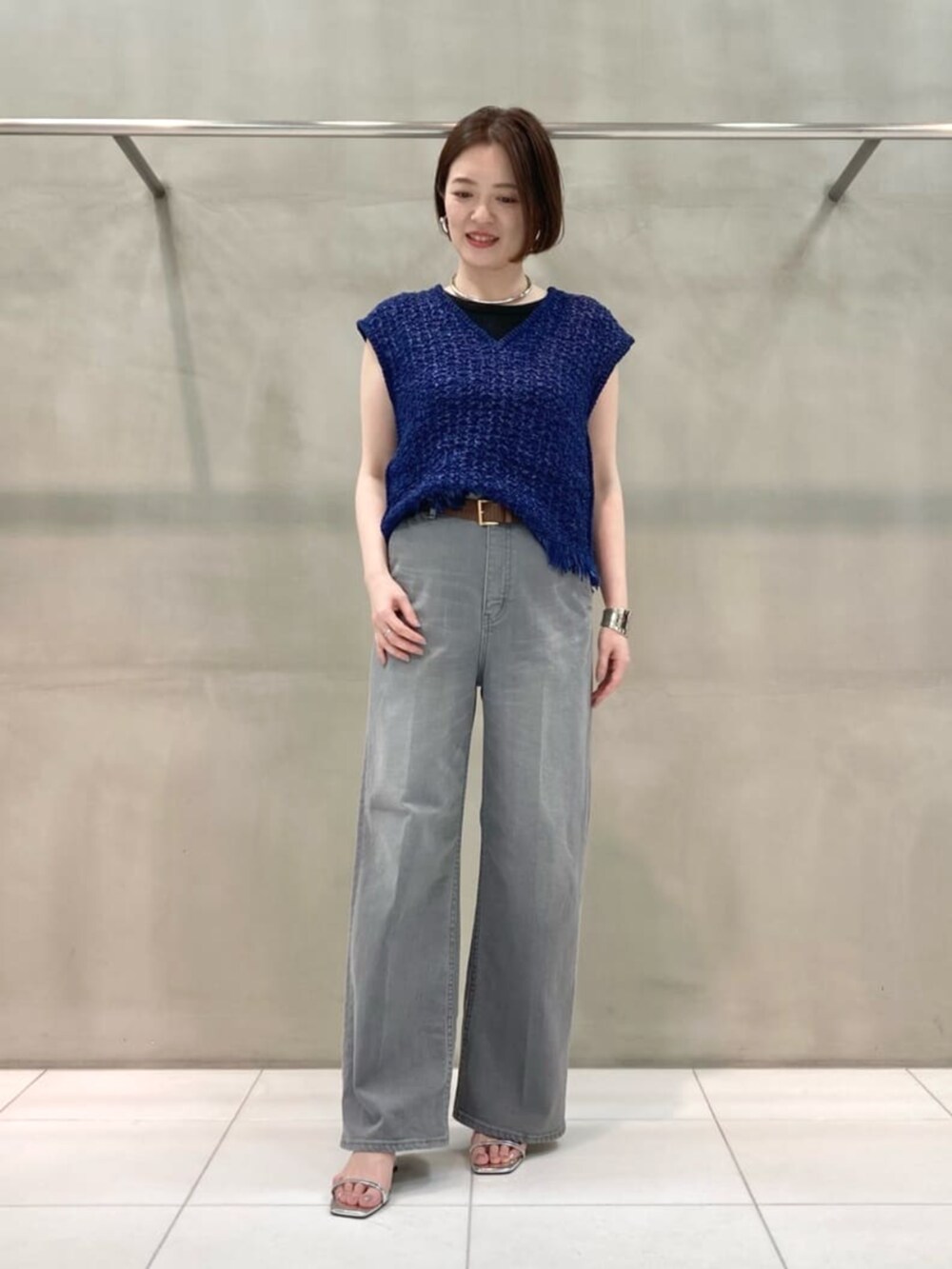 グレー系のデニムパンツ、ブルー系のニット/セーター、シルバー系のブレスレットを着用したレディースの春コーディネートの6枚目の写真