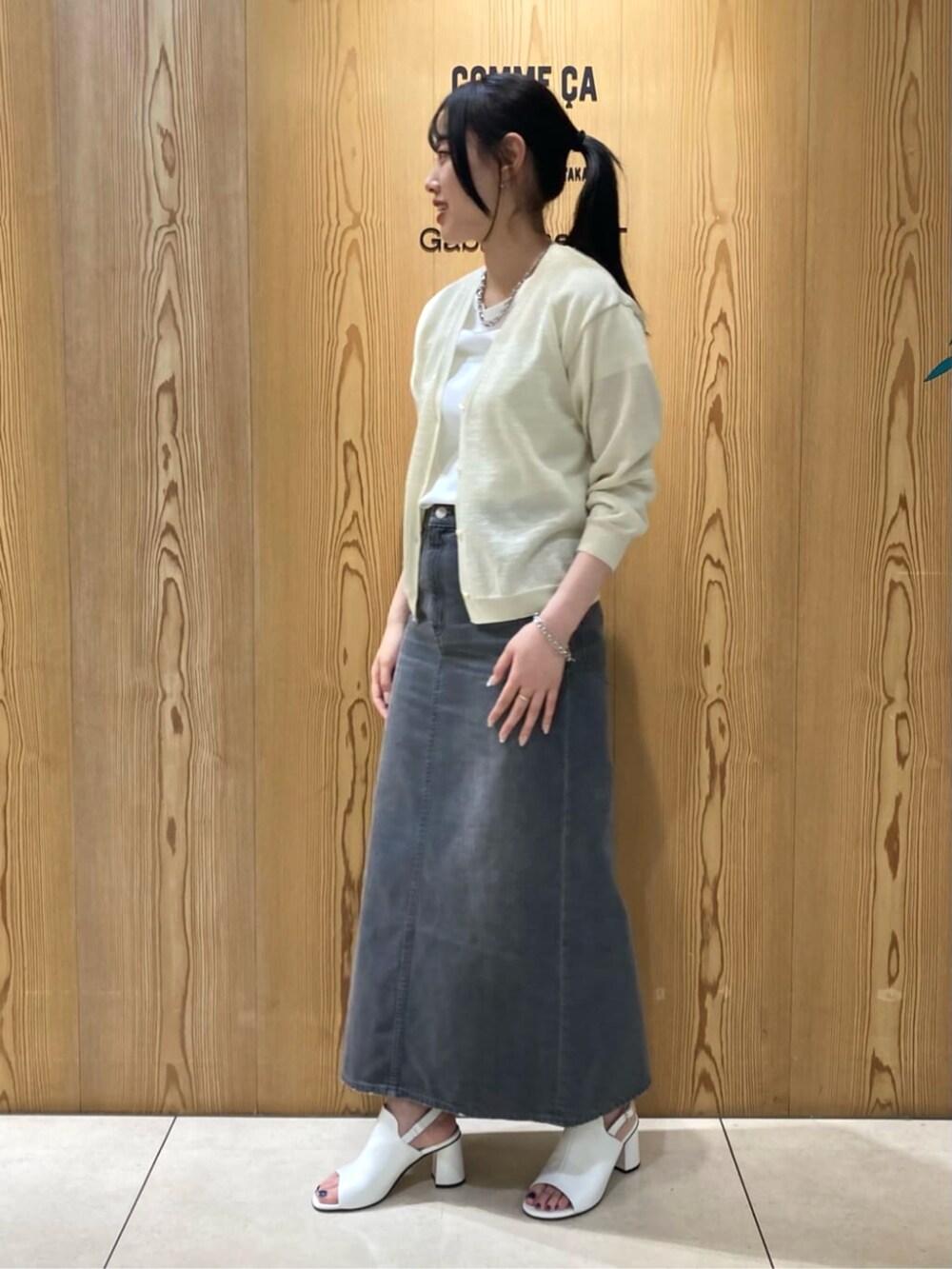 イエロー系のカーディガン/ボレロ、ホワイト系のサンダル、グレー系のスカートを着用したレディースの夏コーディネートの3枚目の写真