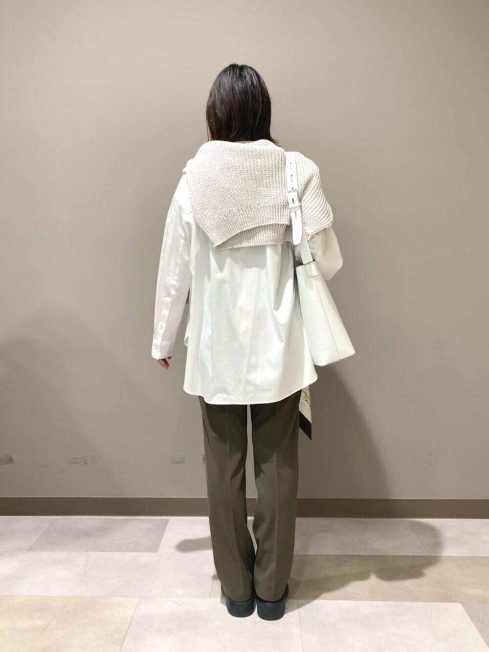 ホワイト系のショルダーバッグ、ホワイト系のシャツ/ブラウス、ブルー系のニット/セーターを着用したレディースの春コーディネートの4枚目の写真