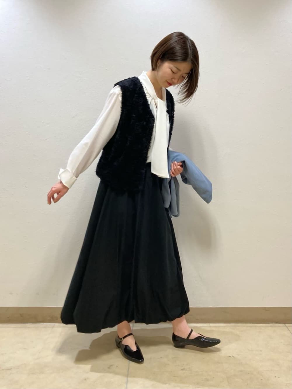 ブラック系のスカート、ブラック系のパンプス、ブルー系のブルゾンを着用したレディースの冬コーディネートの6枚目の写真