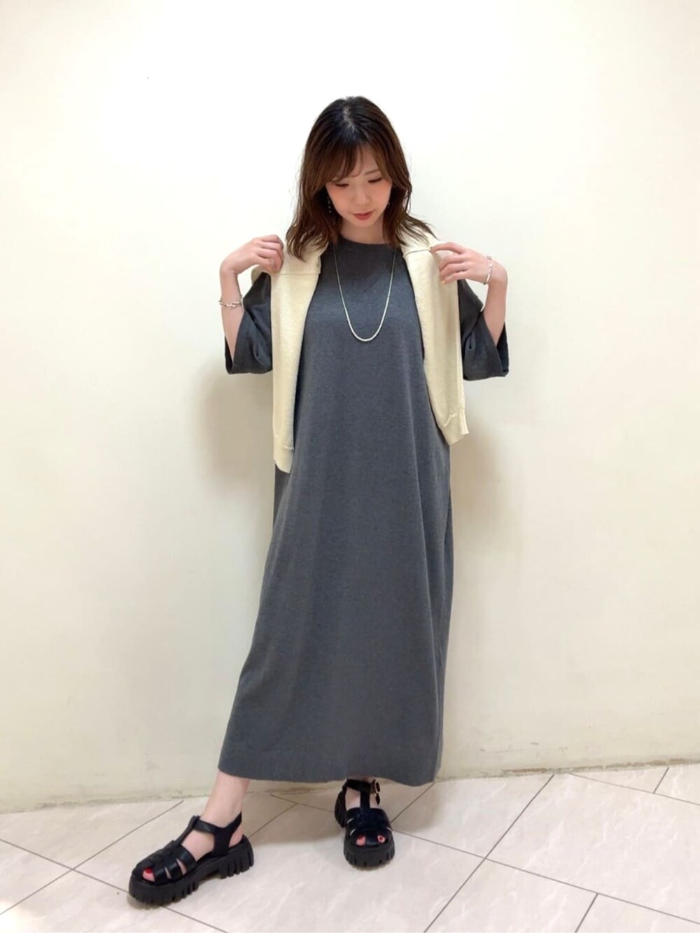 イエロー系のカーディガン/ボレロ、グレー系のワンピース、ホワイト系のネックレスを着用したレディースの春コーディネートの3枚目の写真